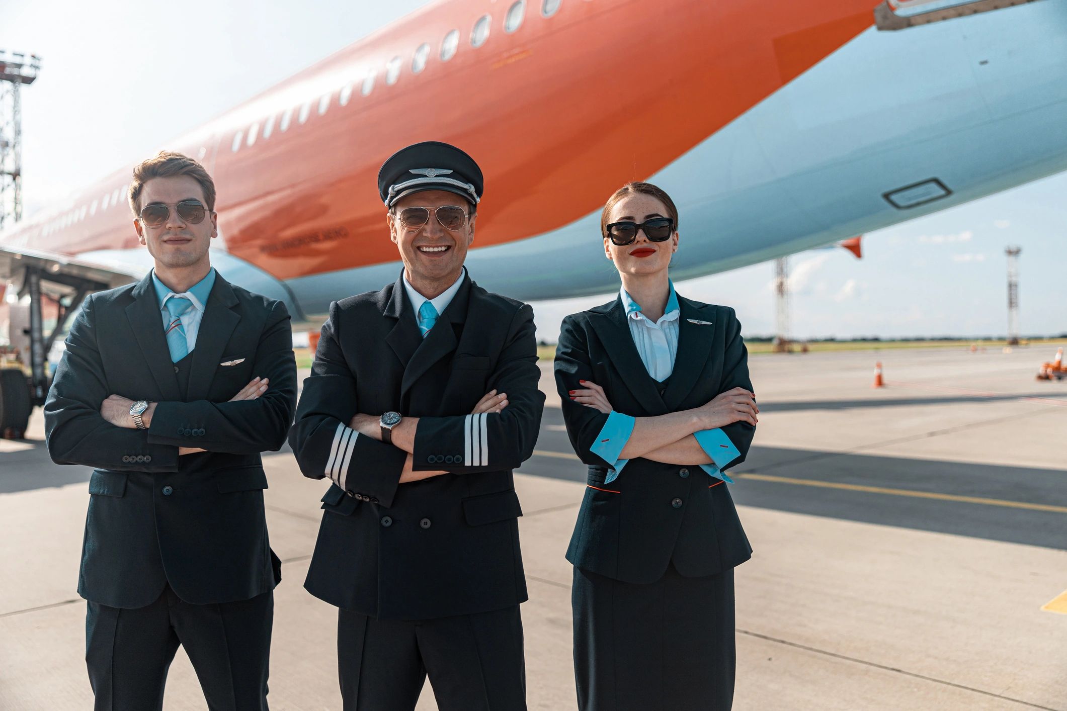 Friendly aviation crew smiling near an airplane