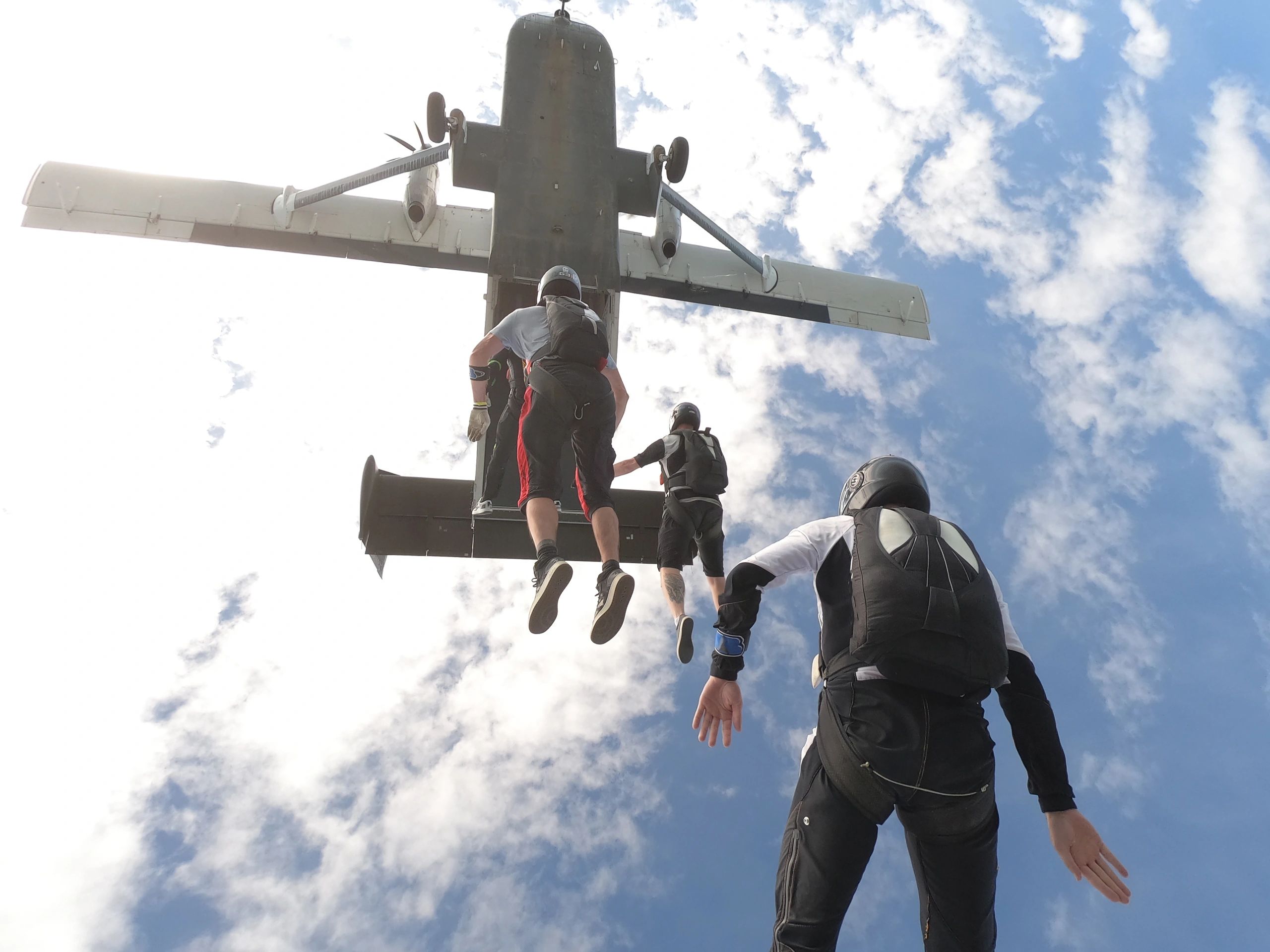 Skydivers in freefall above a rural landscape